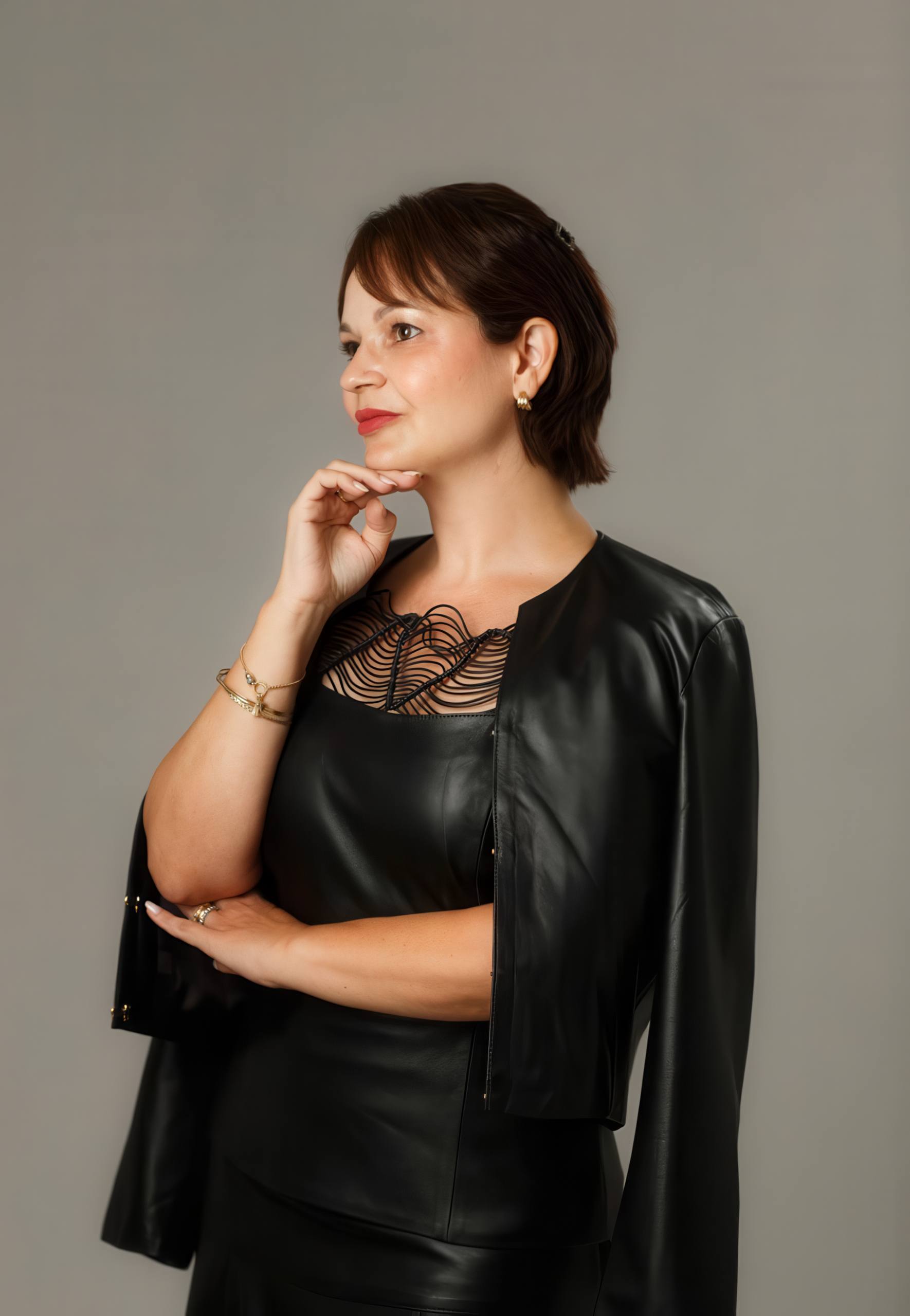 Dra. Yanne Batista de perfil, pensativa, com a mão no queixo, vestida de preto.
